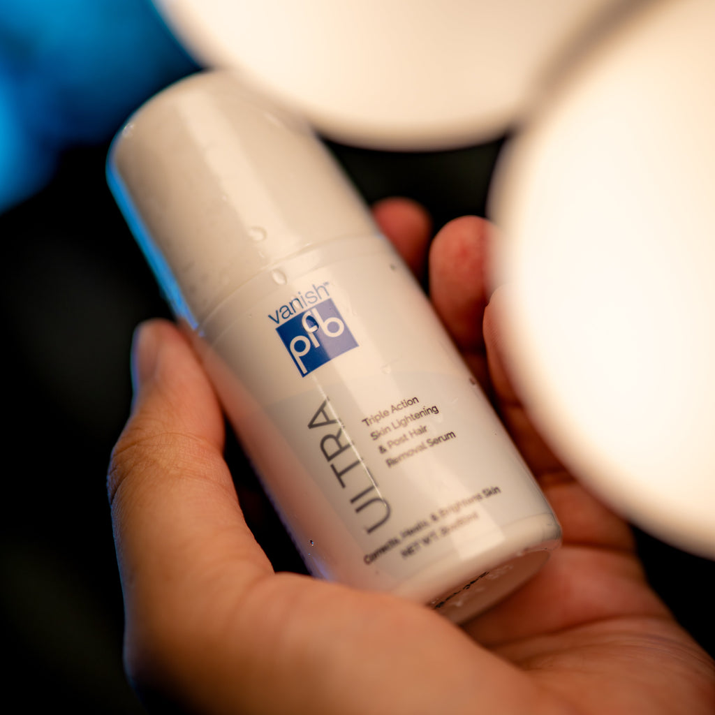 Hand holding a bottle of Ultra hair product with blurred lights in the background